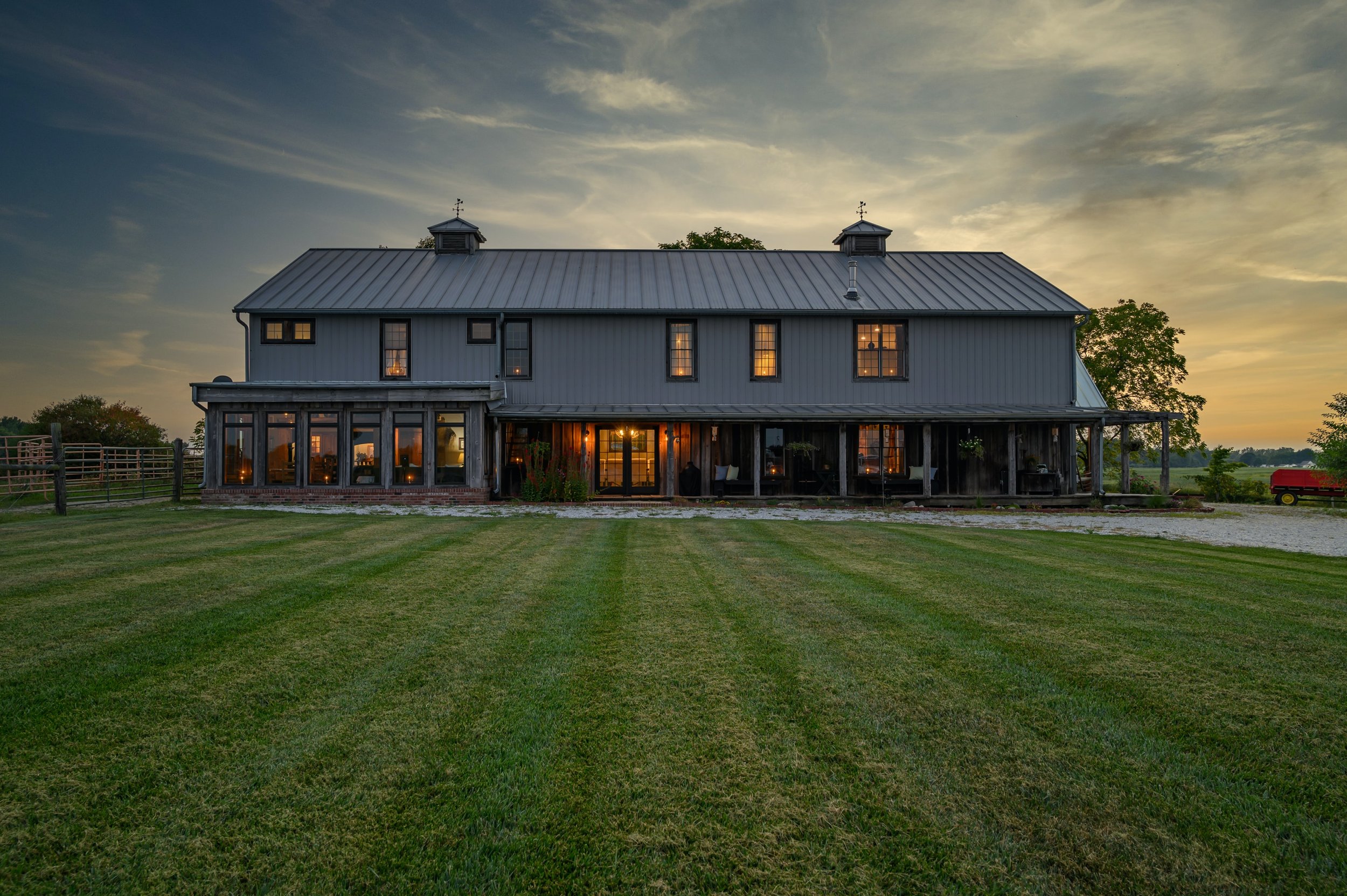 A black barn-style luxury home managed by Scheele Property Management at golden hour in Loveland, Colorado